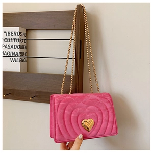 Detail of hot pink quilted crossbody bag with heart embroidery and gold heart lock