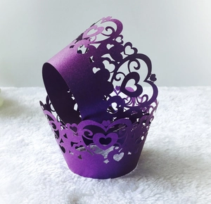 Close-up of laser-cut purple cupcake wrappers with intricate heart and scroll patterns