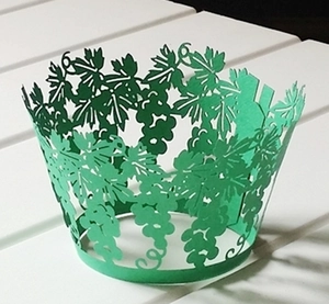 Detail of laser-cut cupcake wrappers with emerald green grapevine and leaf patterns