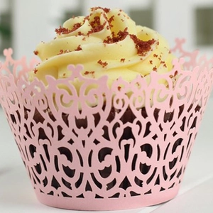 Pink laser-cut cupcake wrappers with elegant scroll patterns for wedding party decor