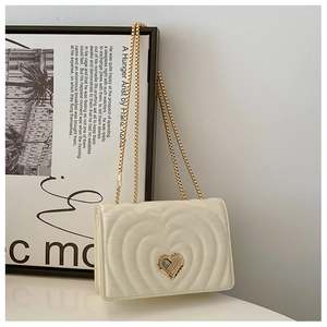 Close-up of heart-shaped quilting and gold heart twist lock on creamy small square bag