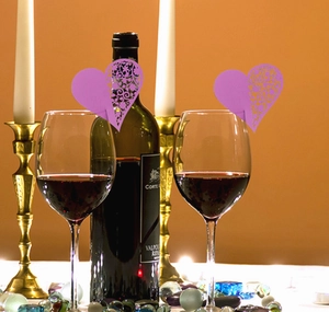 Close-up of laser-cut heart-shaped purple name cards on a wine glass rim