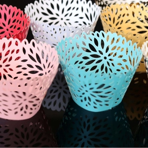 Laser cut floral cupcake liners in multiple colors on a reflective black background