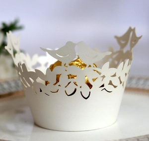 Detailed laser-cut cupcake wrapper with bird and vine patterns for wedding decor