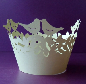 Intricate laser-cut cupcake wrapper featuring bird and leaf patterns on a purple background