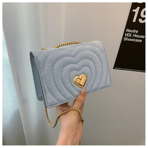 Detailed close-up of light blue heart-quilted crossbody bag with gold heart-shaped lock