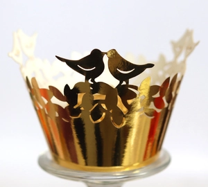Golden laser-cut cupcake wrappers with bird and leaf patterns for wedding decoration