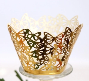 Détail de motifs papillon découpés au laser sur un moule à cupcake doré festonné