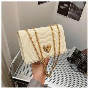 Detail of cream quilted crossbody bag with heart texture and gold heart-shaped twist lock