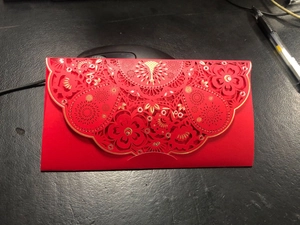 Detail of red hollowed-out greeting card with laser cut floral patterns and gold foil edges
