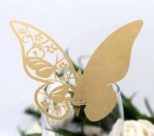 Close-up of golden laser-cut butterfly place card with intricate floral hollow pattern