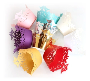 Laser-cut cupcake wrappers with bird and floral patterns in various pearlized colors