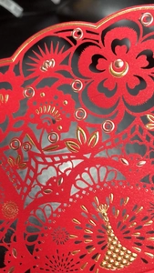 Detail of red hollowed card featuring intricate laser cut patterns and gold stamping foil