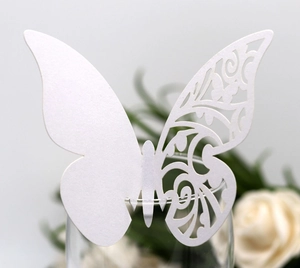 Macro view of white laser-cut butterfly place card with pearl texture on wine glass