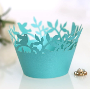 Teal laser cut cupcake wrappers with bird and leaf patterns on pearl paper