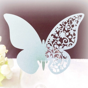 Macro shot of laser-cut butterfly place card with floral hollow pattern on a glass rim