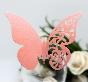 Macro shot of pink laser-cut 3D butterfly place card with intricate hollow patterns on glass