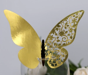 Close-up of golden laser-cut butterfly place card with floral patterns on glass rim