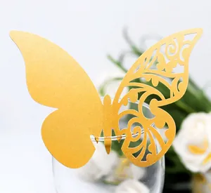Detailed laser-cut gold butterfly place card with floral patterns on a wine glass rim