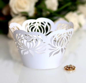 Close-up of laser-cut floral cupcake wrappers in white for wedding party decorations