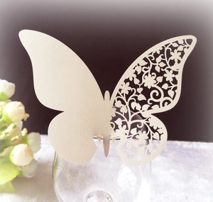 Detailed laser-cut butterfly place card in pearl white on a glass rim for weddings