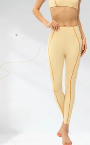 Détail du legging de yoga taille haute avec coutures orange contrastées sur tissu jaune