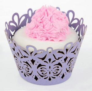 Macro shot of purple laser-cut cupcake wrapper with butterfly patterns on frosting cake