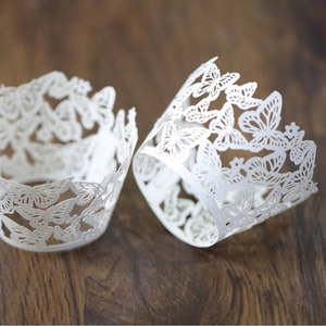 Elegant white laser-cut cupcake wrappers with intricate butterfly patterns for weddings