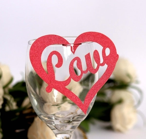 Red glitter heart place card with laser-cut Love design on glass rim for weddings