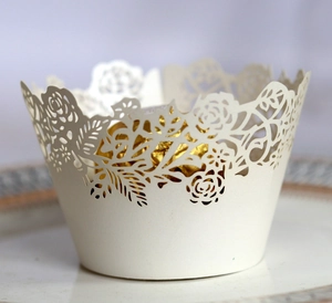 Close-up of laser-cut white pearl paper cupcake wrapper with elegant rose patterns