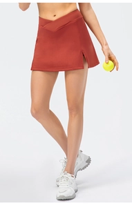 Detail view of brick red tennis skirt with crossover V-waistband and functional side slit