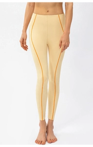 Détail de legging yoga taille haute avec coutures orange sur tissu élastique crème doux