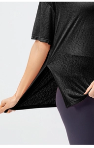 Detail view of the side slit and breathable texture on a black short sleeve sports top