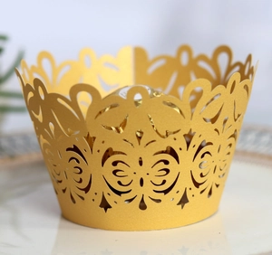 Golden laser-cut hollow cake wrapper with floral patterns on white plate