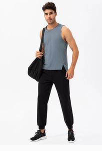 Male athlete wearing a gray quick-dry fitness vest with side slits and black joggers