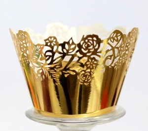 Detail of laser-cut gold cupcake wrapper with floral patterns for wedding decoration