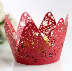 Macro view of red laser-cut cupcake wrapper with snowflake patterns and crown design