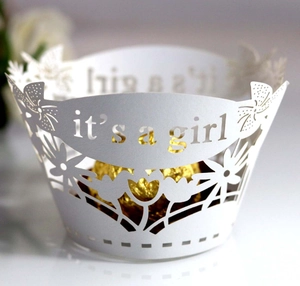 Detail of white laser-cut cupcake wrapper featuring 'It's a Girl' text and floral design