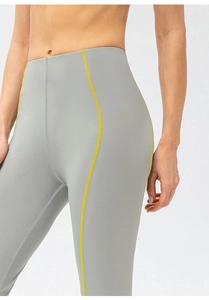 Gros plan d'un legging de yoga taille haute avec coutures jaunes contrastées et tissu gris