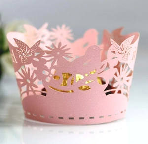 Detail of pink laser-cut cupcake wrapper with floral and bird hollow patterns