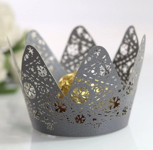Macro detail of laser-cut crown cupcake wrapper with snowflake patterns and glitter finish