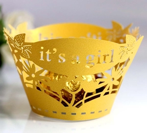 Macro detail of yellow laser-cut cupcake wrapper with it's a girl text and floral patterns