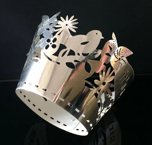 Detail of silver hollow metal cake wrapper with It's a girl text and bird floral patterns