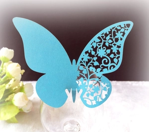 Laser-cut sky blue butterfly place card with floral hollow pattern on wine glass rim