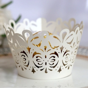 White laser-cut cupcake wrappers with elegant hollow patterns for wedding cake decoration