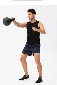 Male athlete posing in breathable black workout tank top and navy shorts with kettlebell