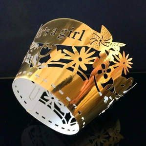 Detail of golden 'it's a girl' laser-cut cupcake wrapper for baby shower parties