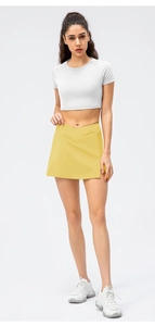 Detailed side view of white crop top and yellow tennis skirt with split hem design
