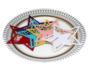Colorful laser cut star place cards in six vibrant colors on a decorative white porcelain plate