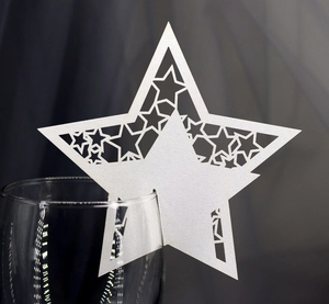 Macro detail of white star-shaped laser-cut wine glass place card for wedding decor